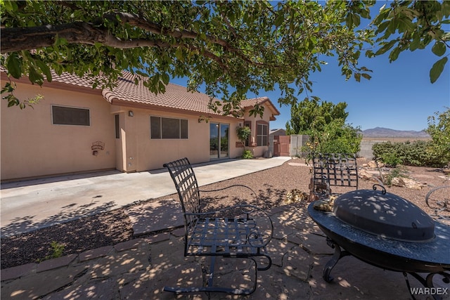 back of house featuring a patio, a mountain view, a tiled roof, a gate, and stucco siding