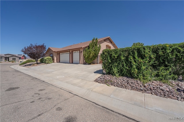 view of front of house featuring a garage, concrete driveway, and stucco siding