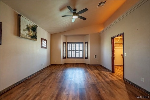 spare room featuring lofted ceiling, visible vents, baseboards, and wood finished floors