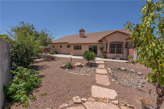 back of house featuring a fenced backyard, a tile roof, stucco siding, a chimney, and a patio area