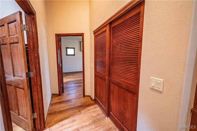 hall with light wood-style flooring and baseboards