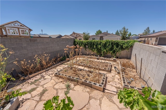 view of yard featuring a fenced backyard, a residential view, and a vegetable garden