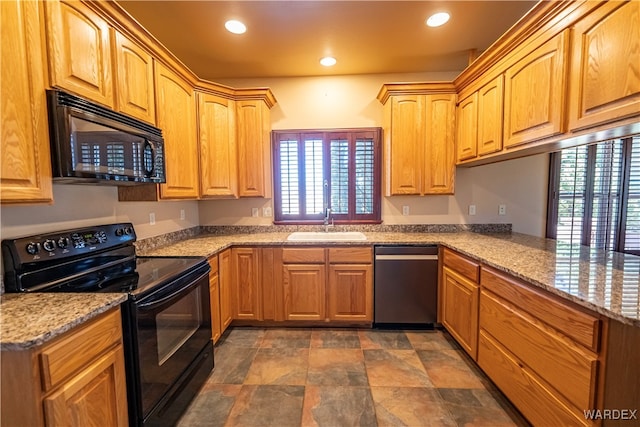 kitchen with light stone counters, recessed lighting, a sink, and black appliances