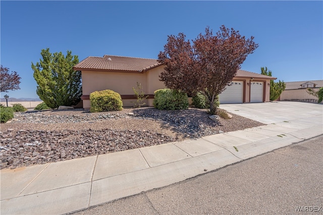 view of front of house with a garage, driveway, a tiled roof, and stucco siding