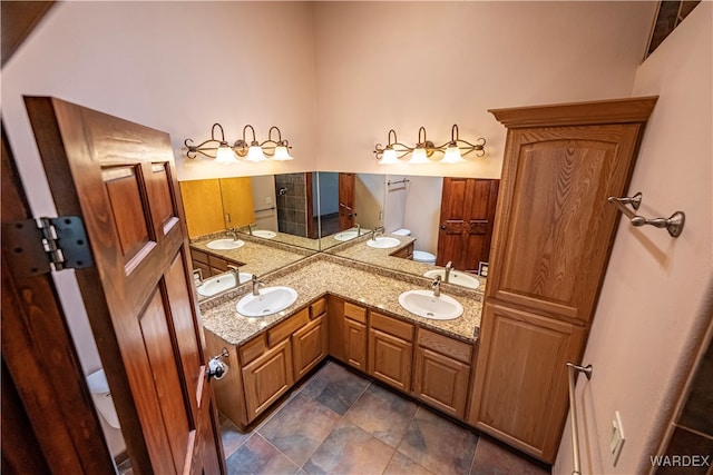 full bath featuring toilet, double vanity, and a sink