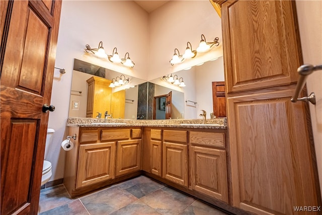 bathroom featuring a sink, toilet, and double vanity