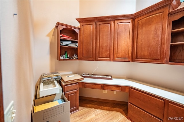 unfurnished office featuring light wood-style floors and built in desk