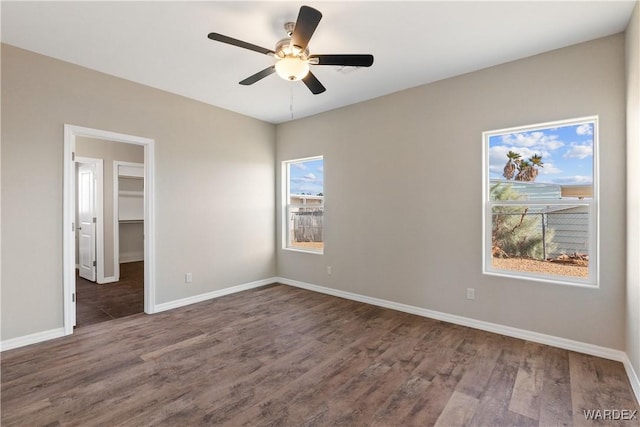 spare room with dark wood finished floors, a ceiling fan, and baseboards