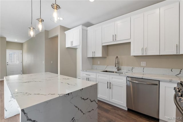 kitchen with white cabinets, appliances with stainless steel finishes, light stone counters, a center island, and decorative light fixtures