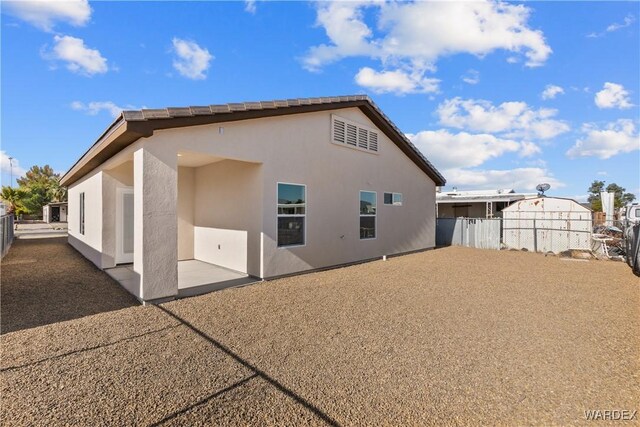 rear view of property with a patio area, fence, and stucco siding