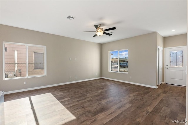 spare room with a ceiling fan, dark wood finished floors, visible vents, and baseboards