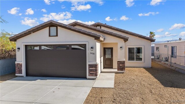 view of front facade with concrete driveway, an attached garage, fence, and stucco siding