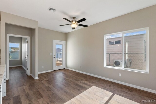 spare room with dark wood-style floors, baseboards, visible vents, and a ceiling fan