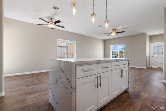 kitchen with a center island, decorative light fixtures, dark wood finished floors, visible vents, and white cabinets