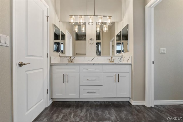 full bath with a sink, baseboards, and double vanity