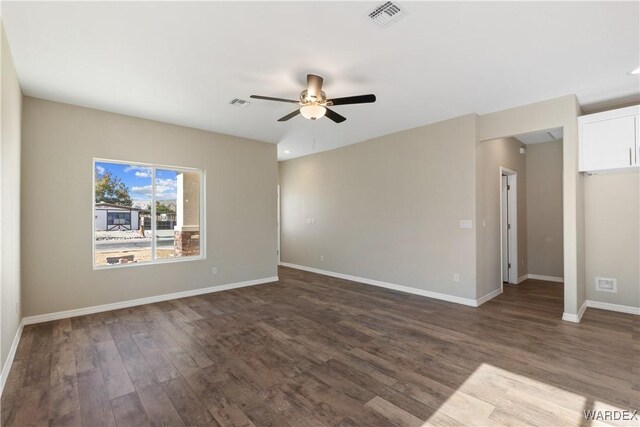 spare room featuring dark wood-style floors, visible vents, ceiling fan, and baseboards