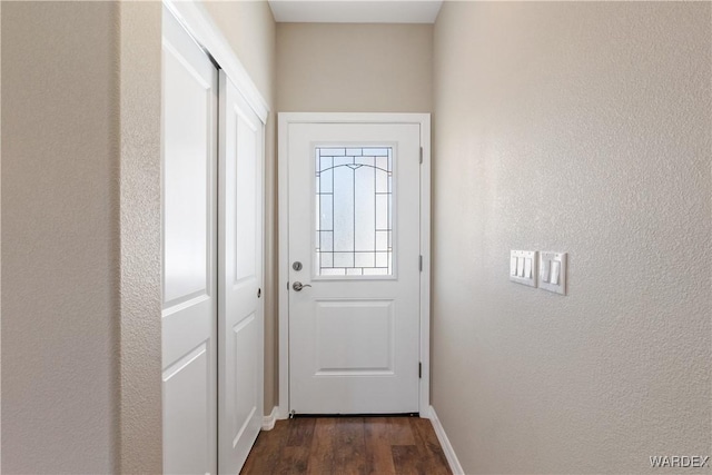 entryway with dark wood-type flooring and baseboards