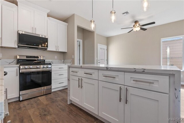 kitchen featuring dark wood-style flooring, light countertops, appliances with stainless steel finishes, a ceiling fan, and white cabinets