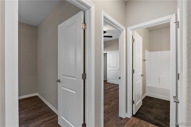 corridor with dark wood-style floors and baseboards