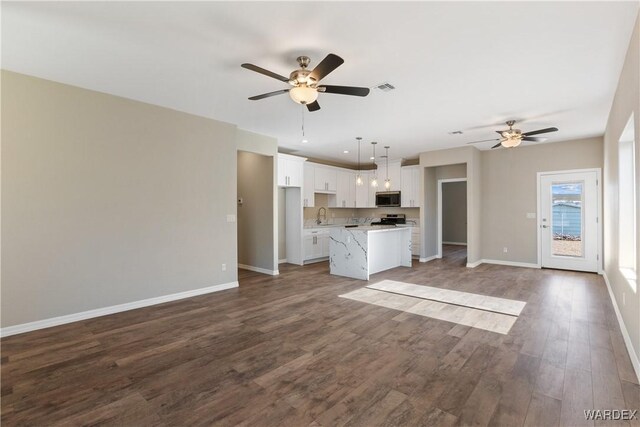 unfurnished living room featuring visible vents, ceiling fan, a sink, wood finished floors, and baseboards