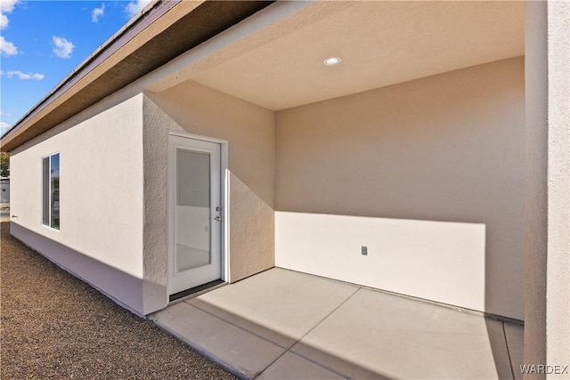 entrance to property with stucco siding and a patio