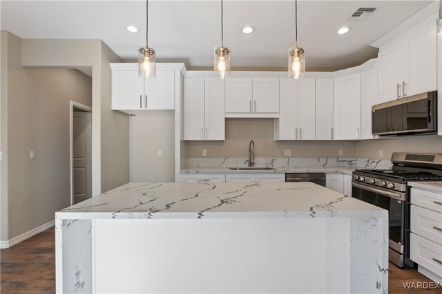 kitchen with appliances with stainless steel finishes, a center island, white cabinetry, and hanging light fixtures