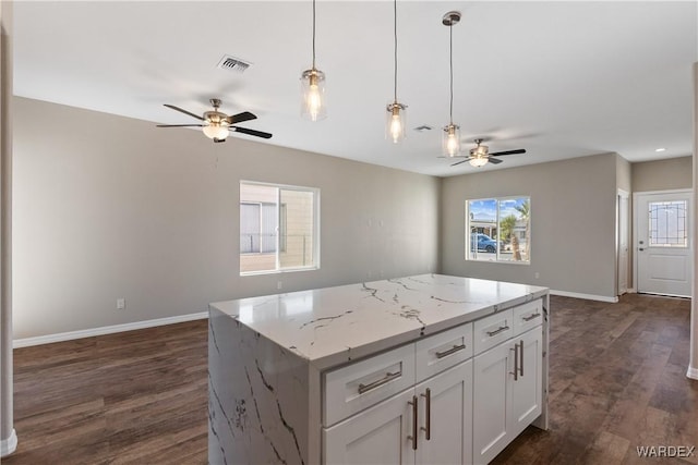 kitchen with light stone counters, visible vents, white cabinetry, open floor plan, and a center island