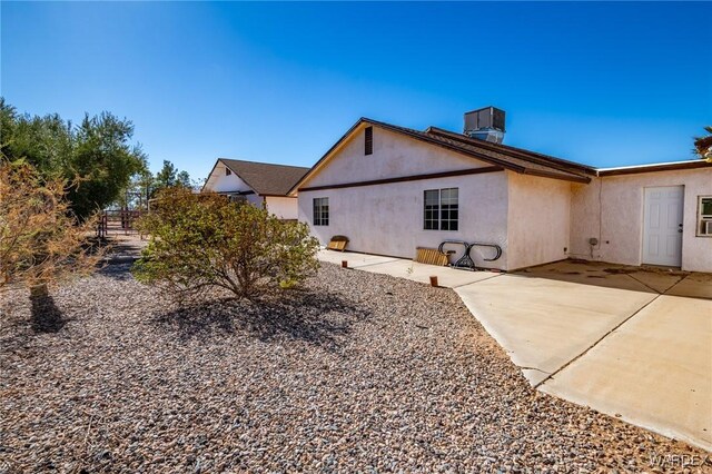 rear view of property featuring a patio, cooling unit, and stucco siding