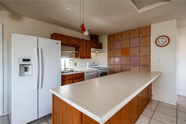 kitchen featuring brown cabinetry, white appliances, light countertops, and a sink