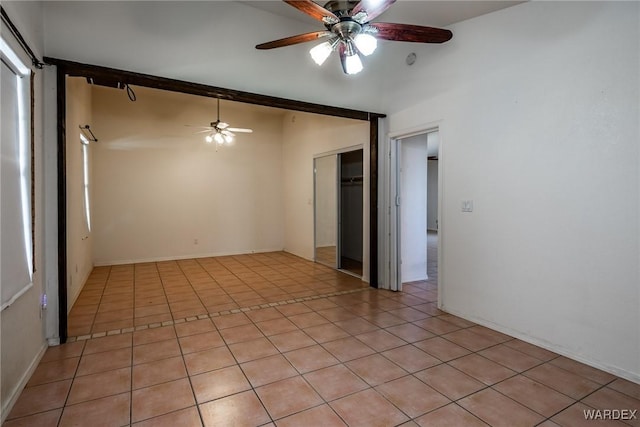 empty room with vaulted ceiling with beams, ceiling fan, and light tile patterned floors