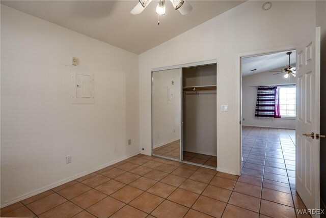 unfurnished bedroom featuring lofted ceiling, light tile patterned floors, a ceiling fan, a closet, and electric panel