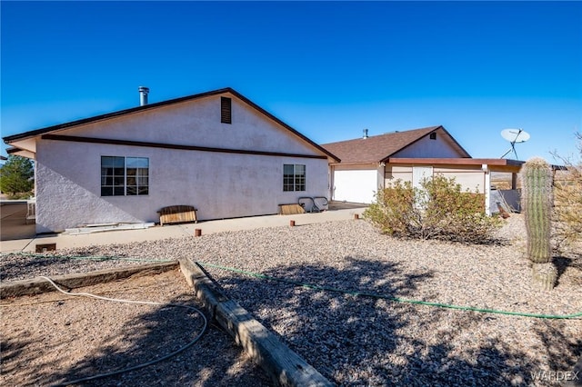 rear view of property featuring stucco siding