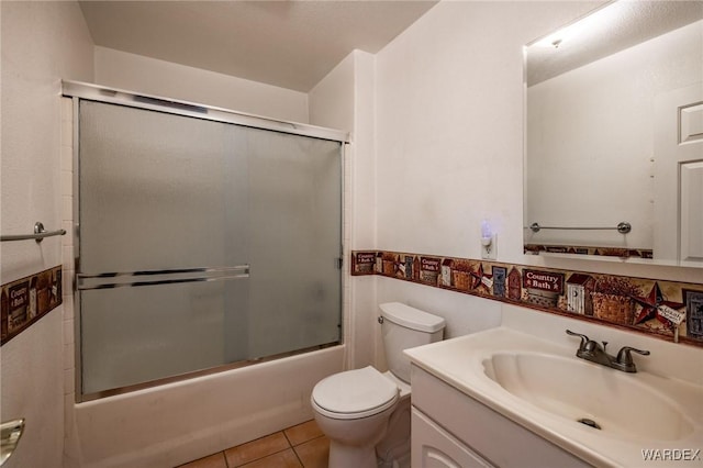 bathroom featuring toilet, combined bath / shower with glass door, tile patterned flooring, and vanity