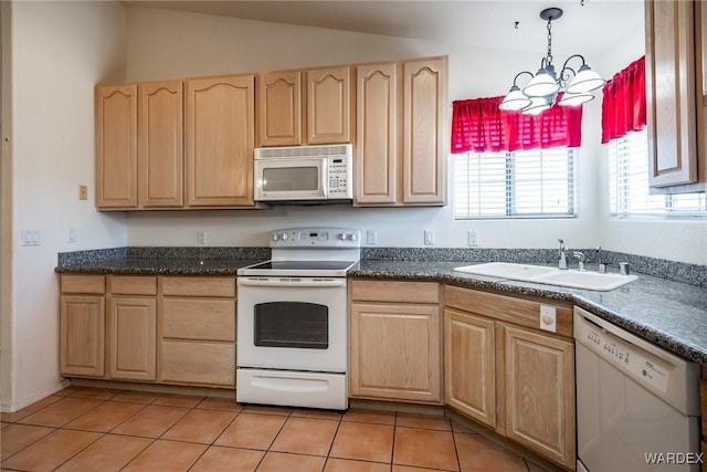 kitchen with decorative light fixtures, light tile patterned floors, light brown cabinets, a sink, and white appliances