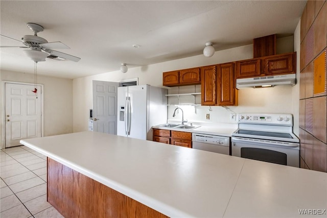 kitchen with white appliances, light countertops, a sink, and under cabinet range hood