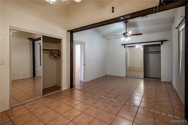 unfurnished bedroom featuring lofted ceiling with beams, light tile patterned floors, ceiling fan, and a closet