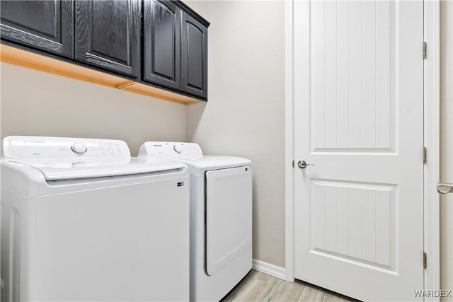2542 E Alterna Dr, Fort Mohave, AZ 86426 - washroom featuring light wood-style flooring, baseboards, washer and clothes dryer, and cabinet space
