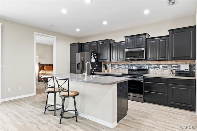 2542 E Alterna Dr, Fort Mohave, AZ 86426 - kitchen with stainless steel appliances, visible vents, light wood-type flooring, a center island with sink, and a kitchen bar