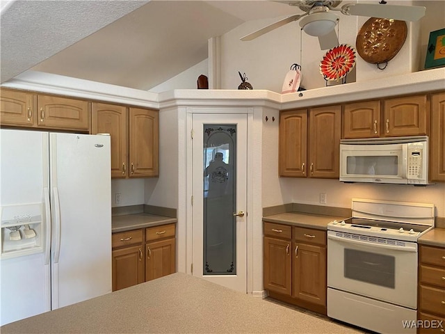 kitchen featuring lofted ceiling, white appliances, light countertops, and brown cabinetry