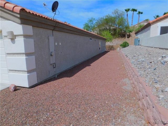 view of side of home featuring stucco siding and a tiled roof