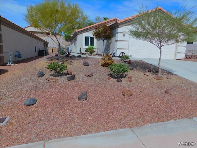 ranch-style home with a tiled roof, stucco siding, an attached garage, concrete driveway, and central AC unit