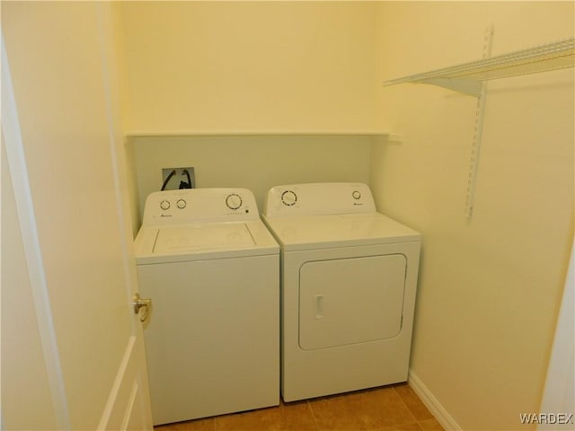 washroom with independent washer and dryer, light tile patterned floors, and laundry area