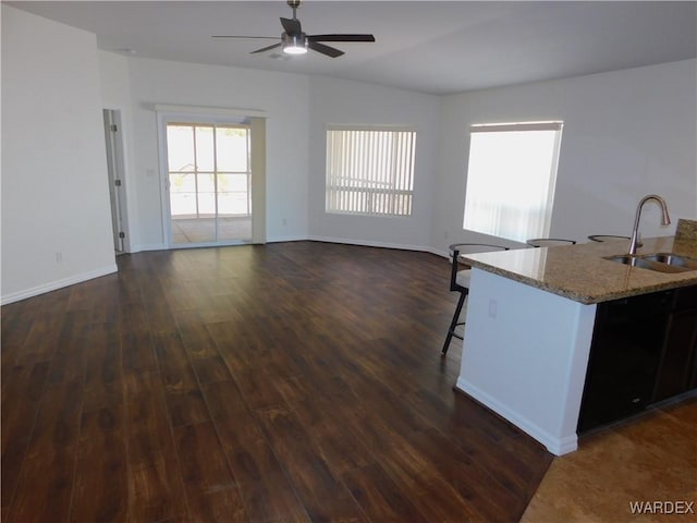 interior space with a sink, baseboards, a ceiling fan, and dark wood-style flooring