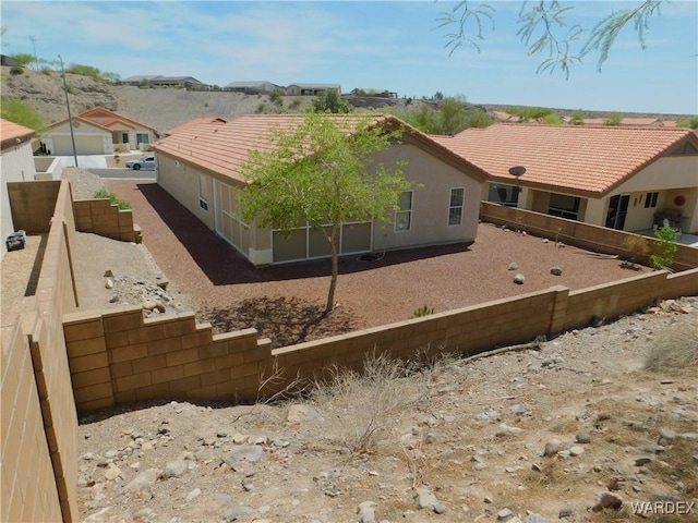 back of property with a fenced backyard, stucco siding, and a tile roof