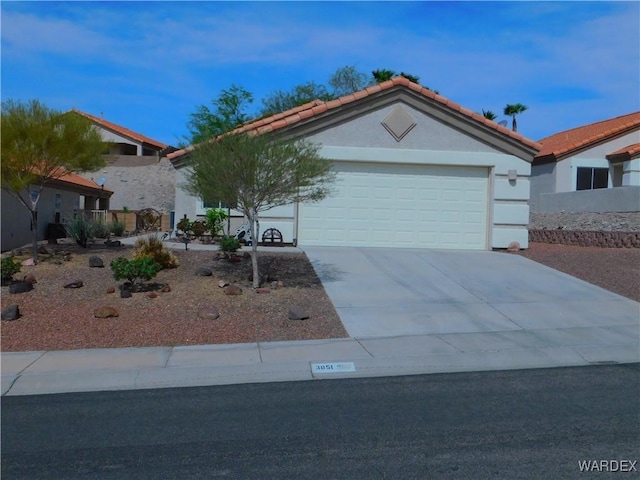 view of front facade with a tile roof, a garage, and concrete driveway