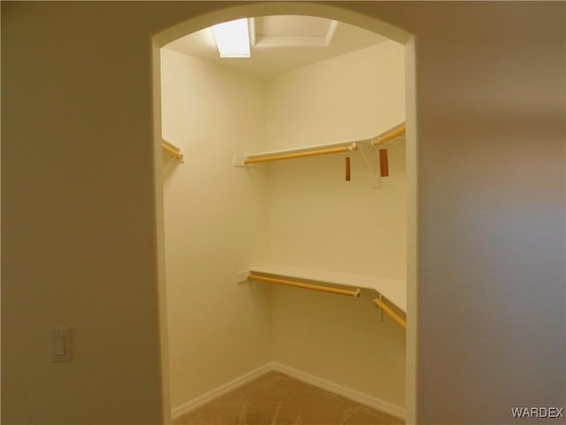 walk in closet with arched walkways and carpet floors
