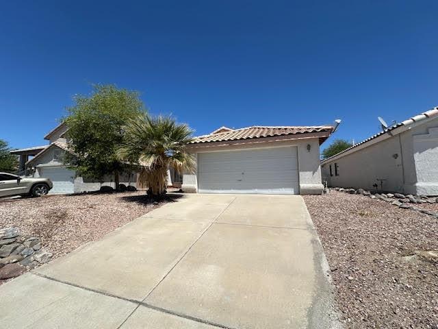 2195 Hijolly Dr, Bullhead City, AZ 86442 - view of front of home featuring driveway, an attached garage, a tiled roof, and stucco siding