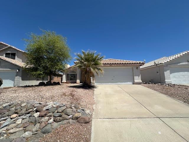 2195 Hijolly Dr, Bullhead City, AZ 86442 - view of front facade featuring a garage, driveway, a tile roof, and stucco siding