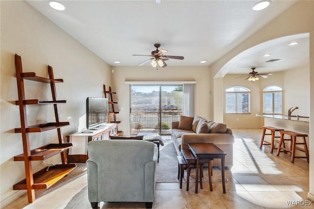 living area featuring light tile patterned flooring, arched walkways, a ceiling fan, and recessed lighting