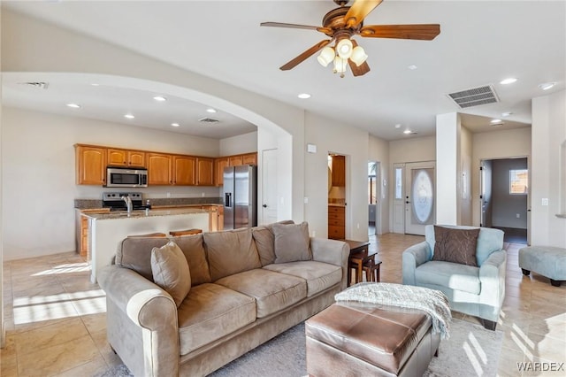 living area with recessed lighting, visible vents, ceiling fan, and arched walkways